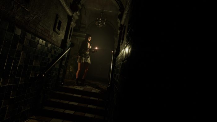 La protagonista di Tormented Souls Caroline Walker in piedi in cima ad alcune scale, con in mano un accendino.