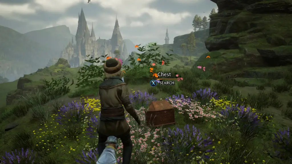 In sella a una scopa accanto a una cassa del tesoro di farfalle in Hogwarts Legacy